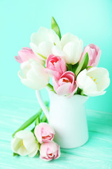 Bouquet of tulips in jug on green background