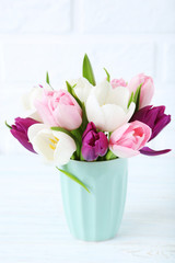 Bouquet of tulips in cup on brick wall background