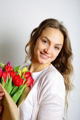 Smiling young woman standing with a bouquet of tulips, looking a