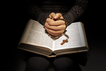 Hands of young woman with holy bible and rosary