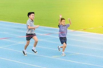 Obraz premium Young Asian boy running on blue track in the stadium