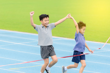 Young Asian boy running on blue track in the stadium