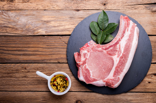 Raw meat on rustic wooden background. Raw pork steak with herbs, oil and spices. Cooking meat. Copy space