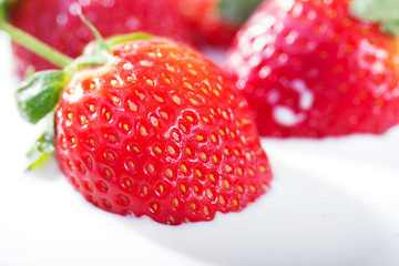 Strawberries falling into fresh bowl of cream