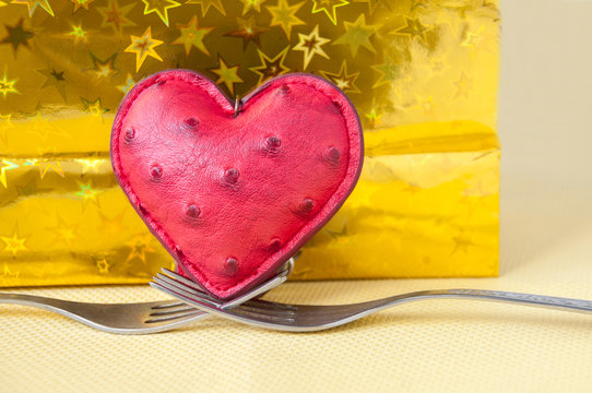 Heart stands on two forks on a gold background