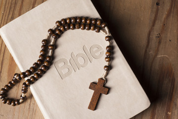 Holy Bible with rosary  on wooden table