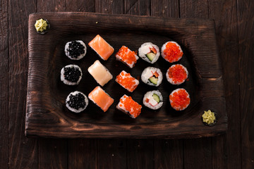 Various kinds of sushi served on a platter with soy sauce, wasabi and pickled ginger.