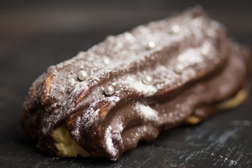 Chocolate eclair on the dark background. Shallow depth of field.