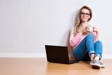 Young creative woman sitting in the floor with laptop. Casual bl