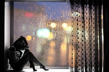 sad girl sitting window lights of the city rain