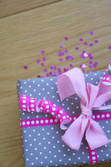 Pacco regalo con fiocco rosa su tavolo di legno