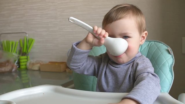 Happy child eating porridge with a big spoon