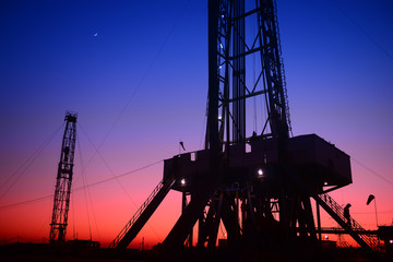 The setting sun under the oil derrick