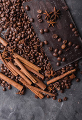 Coffee beans and dark chocolate. Chocolate bar . Background with chocolate. Coffee beans. Cinnamon sticks and star anise.  A large bar of chocolate on gray abstract background.