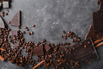 Coffee beans and dark chocolate. Chocolate bar . Background with chocolate. Coffee beans. Cinnamon sticks and star anise.  A large bar of chocolate on gray abstract background.