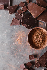 Chocolate  chunks and cocoa powder. Chocolate bar pieces.  A large bar of chocolate on gray abstract background. Background with chocolate. Slices of chocolate, Sweet food photo concept. Copyspace
