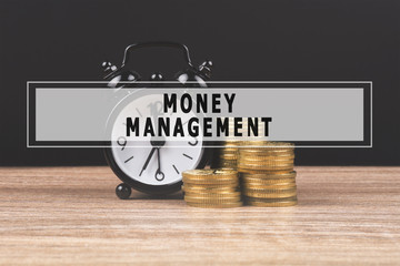 Alarm clock and money coin stack on wooden table and black background with text MONEY MANAGEMENT. Finance concept, copy space.