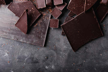 Chocolate chunks. Chocolate bar pieces.  A large bar of chocolate on gray abstract background. Chocolate candies. Background with chocolate. Slices of chocolate. Sweet food photo concept. Copyspace
