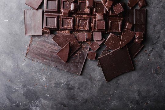 Chocolate chunks. Chocolate bar pieces.  A large bar of chocolate on gray abstract background. Chocolate candies. Background with chocolate. Slices of chocolate. Sweet food photo concept. Copyspace