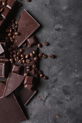 Coffee beans with chocolate  dark chocolate. Broken slices of chocolate. Chocolate bar pieces. A large bar of chocolate on gray abstract background. Coffee beans. Sweet food photo concept. Copyspace