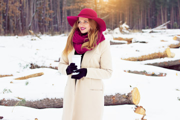 Young, beautiful and stylish red hair girl in coat and hat keeps a thermo cup. Fashion.