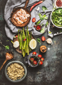 Tasty Quinoa Salad Preparation With Wooden Spoon , Shrimps , Asparagus And Various Healthy Vegetables On Rustic  Kitchen Table Background, Top View