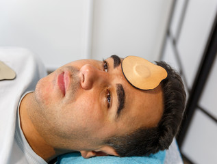 A patient lying on a stretcher with a magnet on his forehead