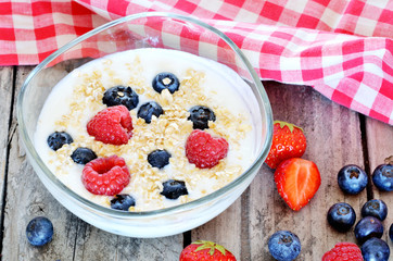 White yogurt in a bowl with oatmeal, blueberries, raspberries and strawberries