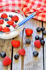 White yogurt in a bowl with oatmeal, blueberries, raspberries and strawberries