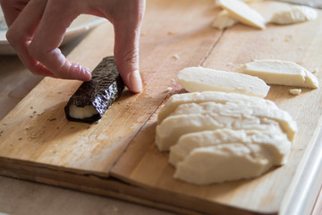 Womens hand making veretarian food, cheese and nori seaweed, Vegetarian fish on wooden board.

