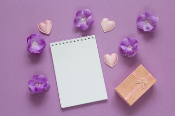 Open blank notebook with gift box, purple flowers and hearts on