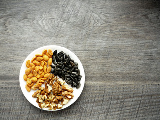 nuts ans sunflower seeds on a plate on wooden background