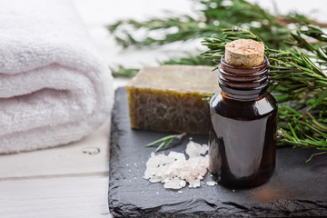 Rosemary essential oil  with  fresh rosemary on dark stone board, selective focus. Spa theme.