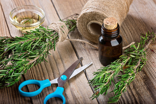 Rosemary essential oil and  fresh rosemary on wooden background, aromatherapy preparation