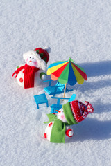 Two cute snowman sunbathing in the snow. Paper beach chairs and a  umbrella. Winter background