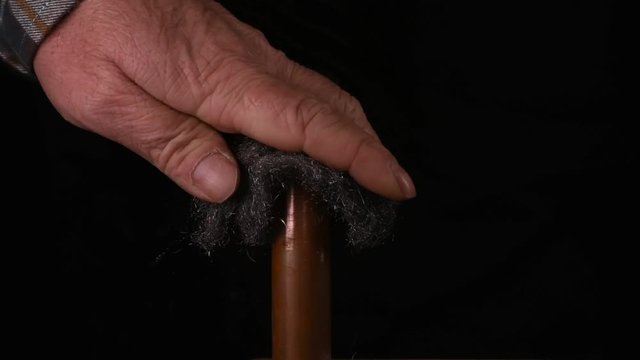 Handwerker reinigt Kupferrohr