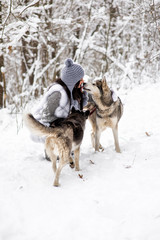 Naklejka premium Girl with Husky in winter forest. Dog licking girl on the cheek
