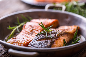 Salmon fillets. Grilled salmon, sesame seeds herb decorationon on vintage pan or black slate board. fish roasted on an old wooden table.Studio shot.