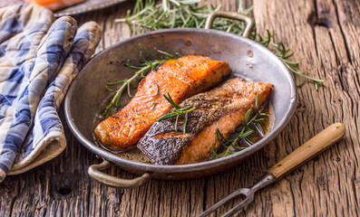 Salmon fillets. Grilled salmon, sesame seeds herb decorationon on vintage pan or black slate board. fish roasted on an old wooden table.Studio shot.