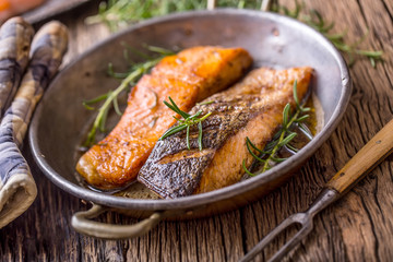 Salmon fillets. Grilled salmon, sesame seeds herb decorationon on vintage pan or black slate board. fish roasted on an old wooden table.Studio shot.