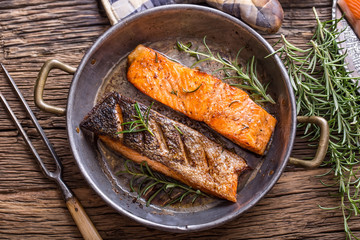 Salmon fillets. Grilled salmon, sesame seeds herb decorationon on vintage pan or black slate board. fish roasted on an old wooden table.Studio shot.