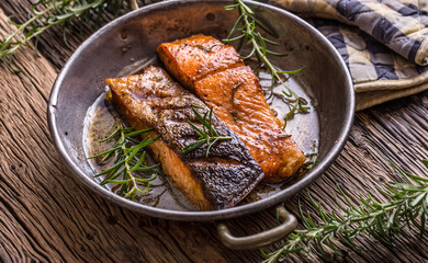 Salmon fillets. Grilled salmon, sesame seeds herb decorationon on vintage pan or black slate board. fish roasted on an old wooden table.Studio shot.