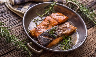 Salmon fillets. Grilled salmon, sesame seeds herb decorationon on vintage pan or black slate board. fish roasted on an old wooden table.Studio shot.