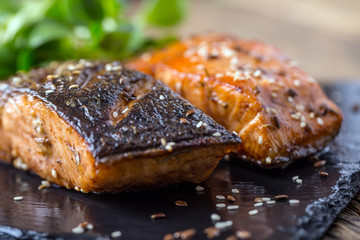 Salmon fillets. Grilled salmon, sesame seeds herb decorationon on vintage pan or black slate board. fish roasted on an old wooden table.Studio shot.