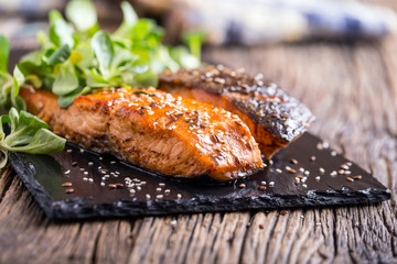 Salmon fillets. Grilled salmon, sesame seeds herb decorationon on vintage pan or black slate board....
