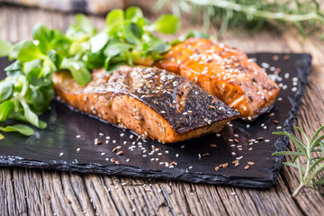 Salmon fillets. Grilled salmon, sesame seeds herb decorationon on vintage pan or black slate board. fish roasted on an old wooden table.Studio shot.