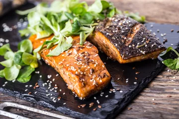 Fotobehang Salmon fillets. Grilled salmon, sesame seeds herb decorationon on vintage pan or black slate board. fish roasted on an old wooden table.Studio shot. © weyo