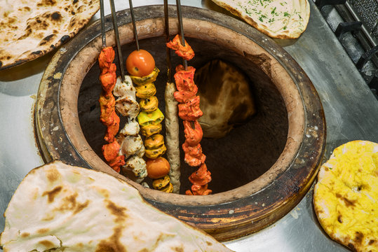 Tandoori chicken or lamb shashlik or kebab on skewers grilled in indian tandoor