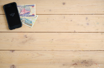 Banknotes of Nigerias on the wooden table under the smartphone