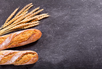 bread with wheat ears on dark board